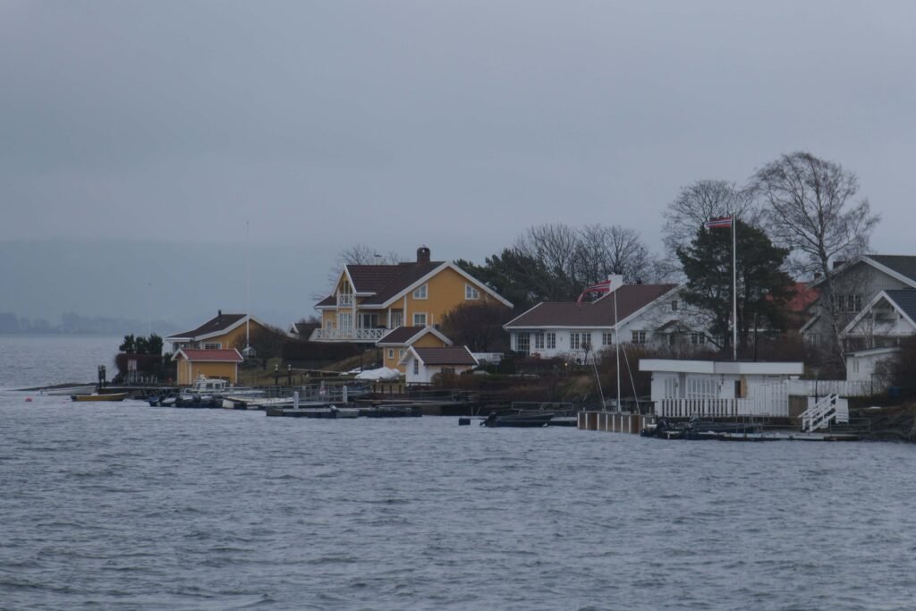 Sailing the moody Oslofjord in winter, passing quaint and colourful island cabins!